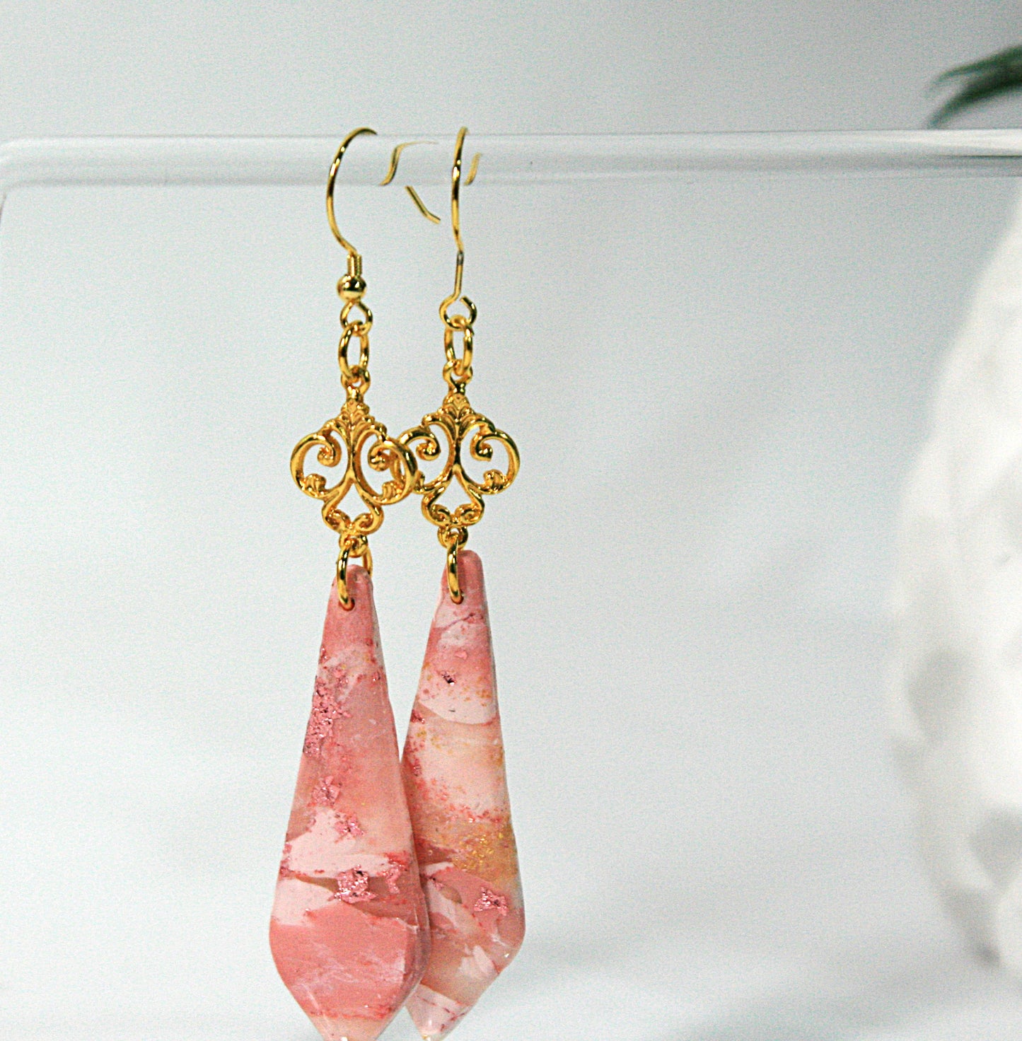 Pink teardrop earrings with gold hooks on a white background