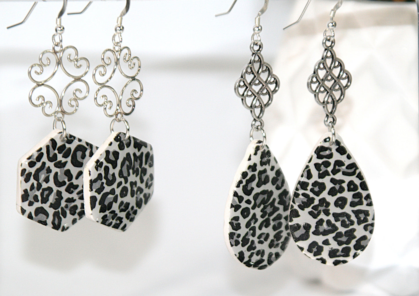 Pair of earrings with leopard print teardrop and hexagonal designs on a white background
