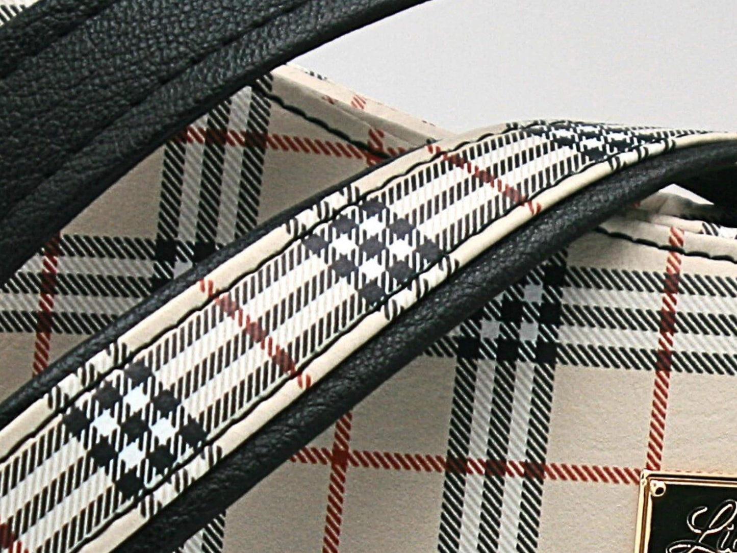 The adjustable shoulder strap is created with the two fabrics use in the bag, the tartan vinyl and the black faux leather.