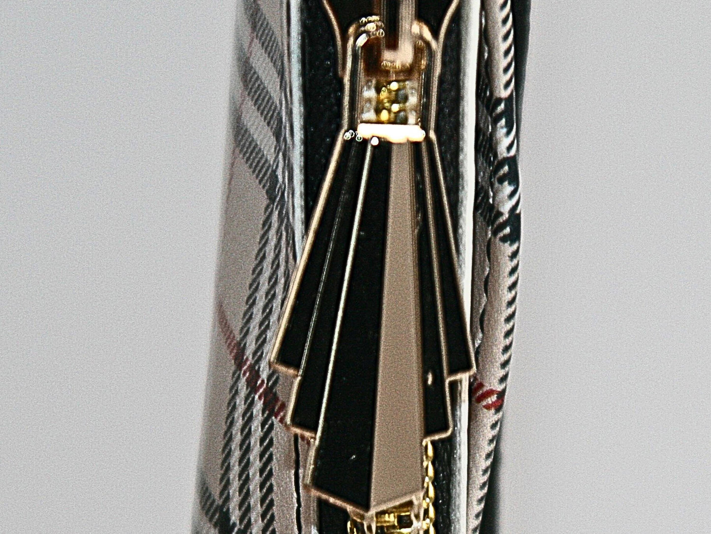 This is the close up of the unique gold hardware gatsby zipper pull used in the Sand Tartan Collection.