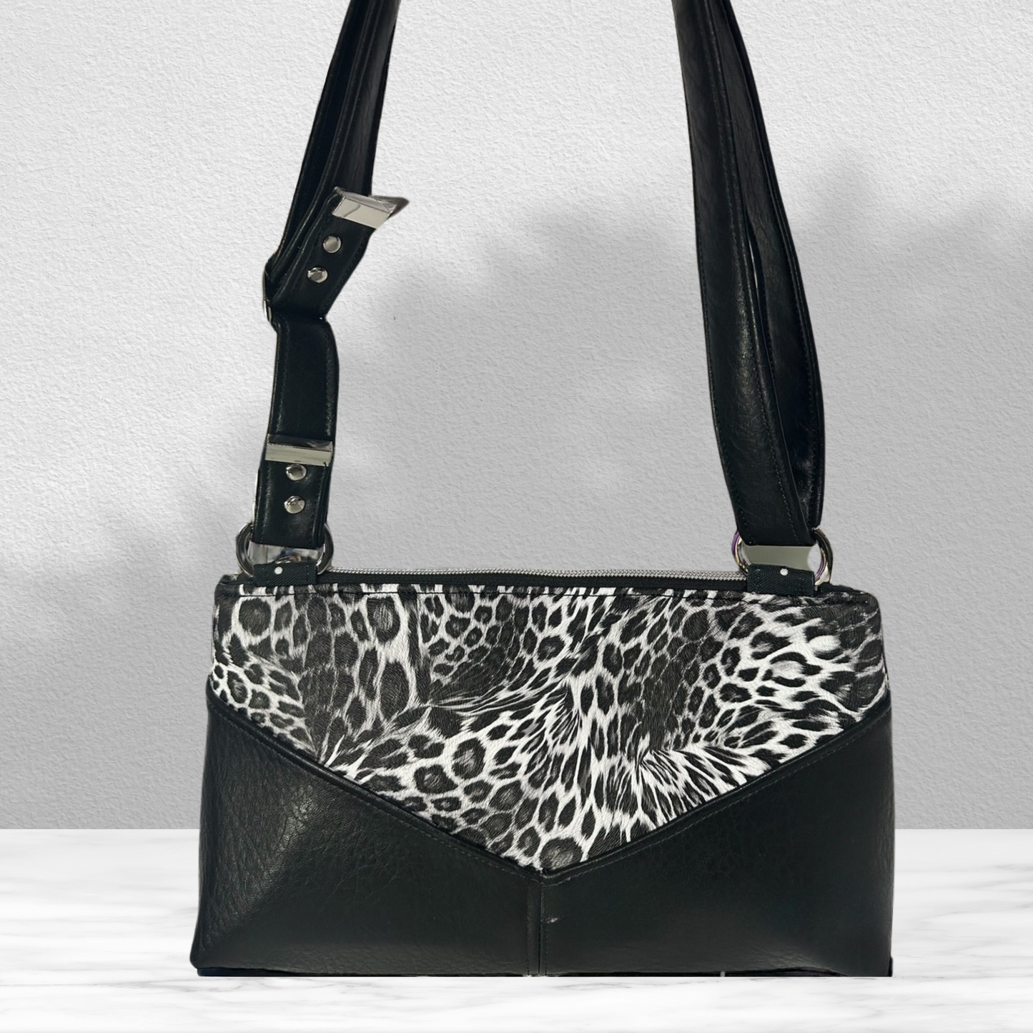 The back view of the Stylish Animal Print Crossbody Purse – Designed with Black Leopard Vinyl, Faux Leather Trim, Silver Hardware, and a Comfortable Adjustable Strap.