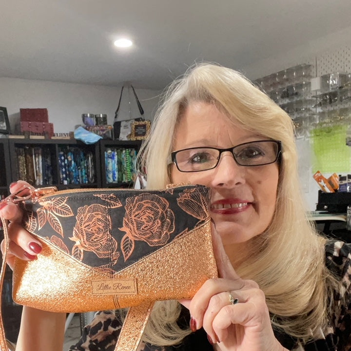  Small yet statement-making Harlequin wristlet, featuring copper vinyl and black faux leather, a soft cotton copper and black interior lining, and a convenient interior zip pocket. Finished with rose gold heart zipper pulls and hardware, this wristlet blends sophistication and practicality.