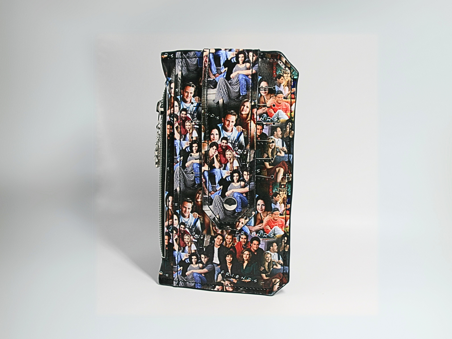  FRIENDS Central Perk-themed Purse Pal slim wallet featuring a snap flap closure to securely hold credit cards. Designed with six card slots, a cash slip pocket, and a zippered coin pocket. Accented with a Central Perk zipper pull, silver hardware, and a compact, stylish design. A must-have accessory for fans of the classic sitcom who love functional and trendy wallets.