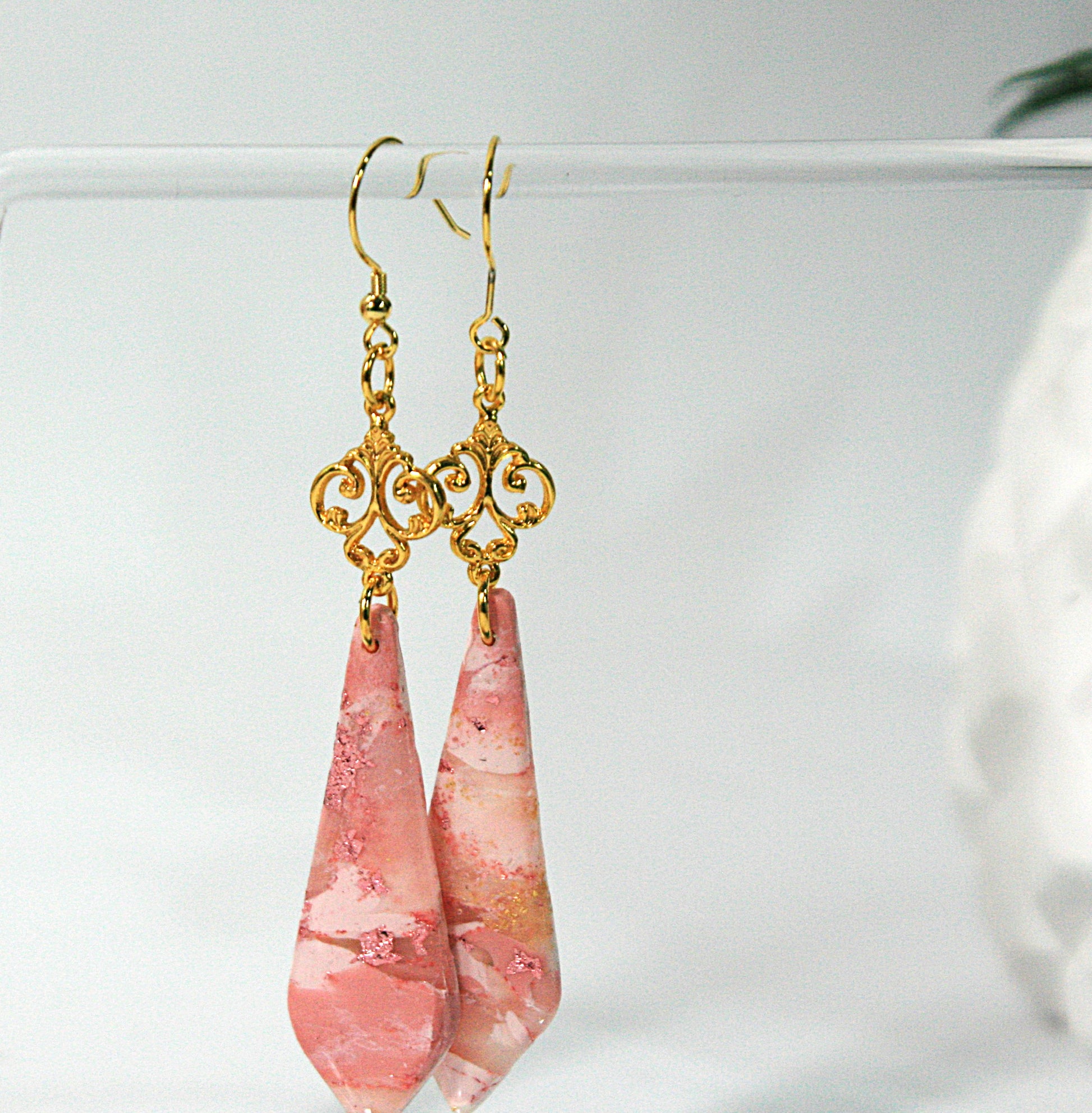 Pink teardrop earrings with gold hooks on a white background
