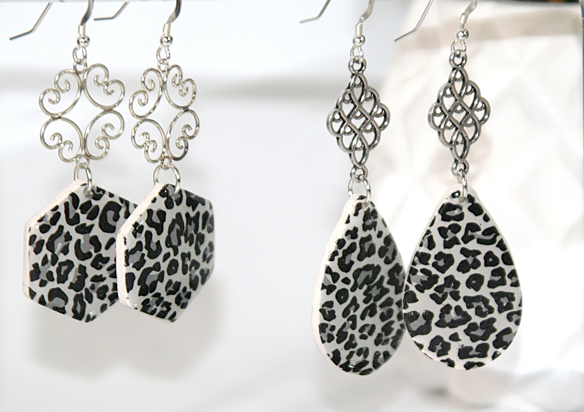 Pair of earrings with leopard print teardrop and hexagonal designs on a white background