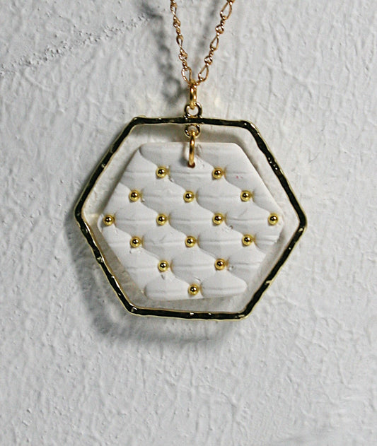White polymer clay with quilted texture hexagon pendant hanging on a gold plated filigree chain