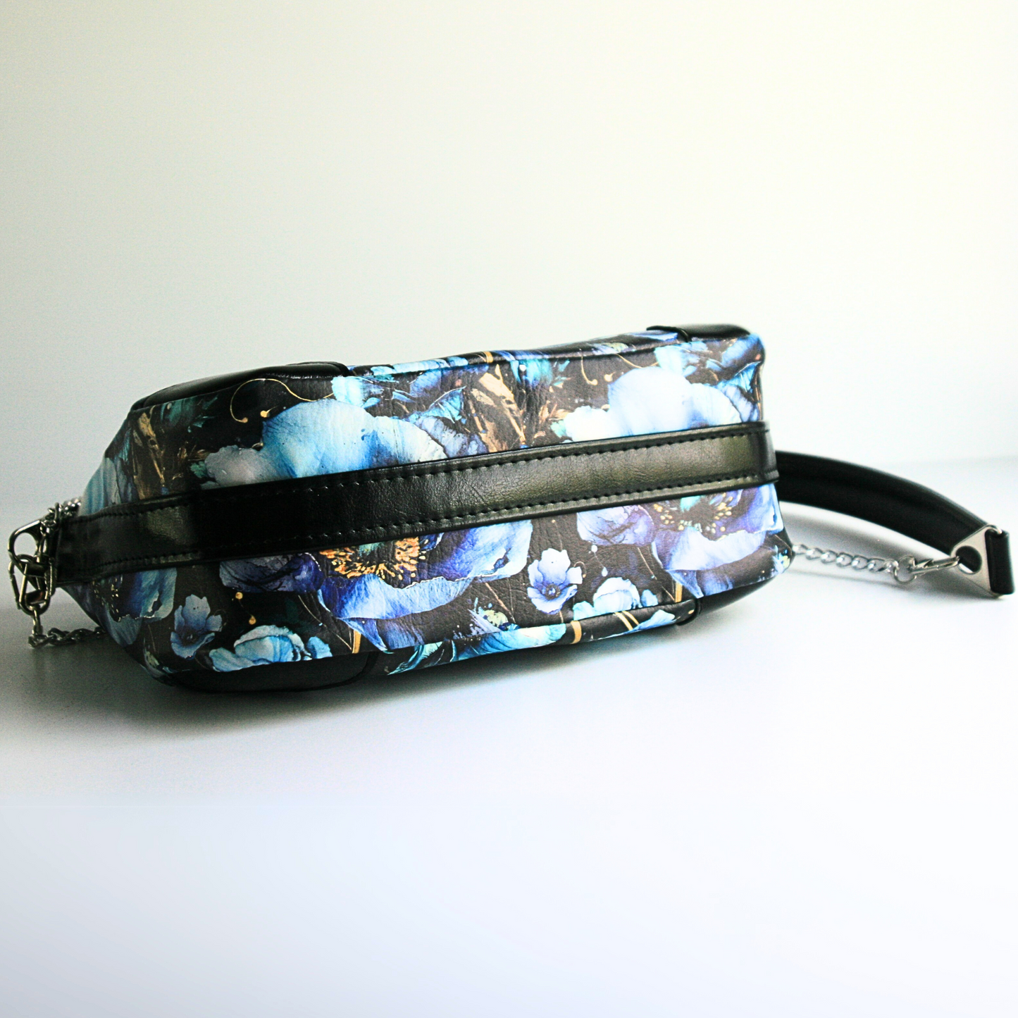 the bottom of the blue poppies shoulder bag shows the strap connector which goes down and under the purse
