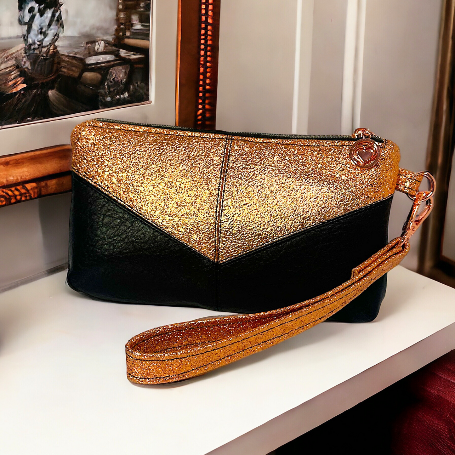 Stylish Harlequin wristlet crafted from copper vinyl and black faux leather, designed with a secure interior zip pocket and a cotton copper and black lining. The elegant rose gold heart zipper pulls and hardware add a luxurious touch, making it a fashionable and functional accessory.
