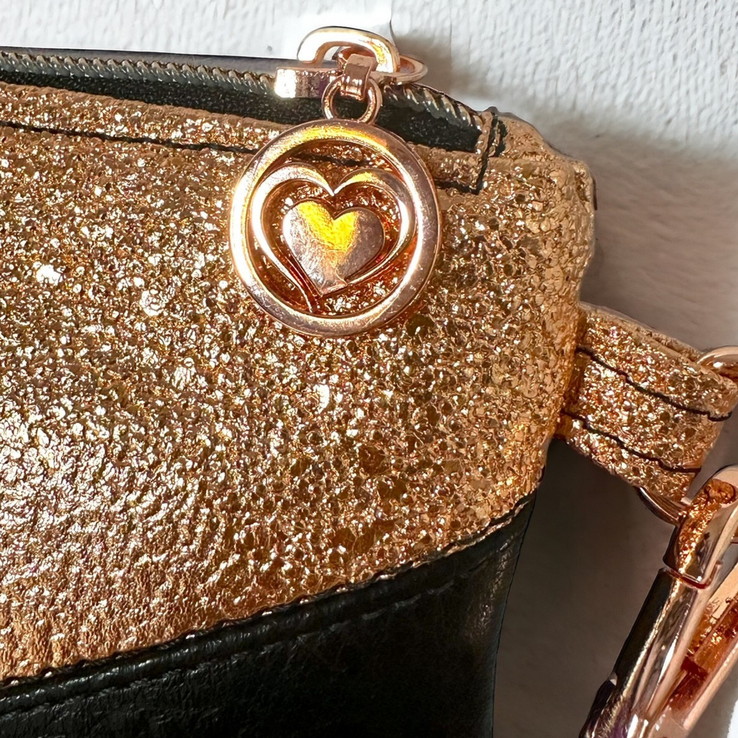  The elegant rose gold heart zipper pulls and hardware add a luxurious touch, making it a fashionable and functional accessory.
