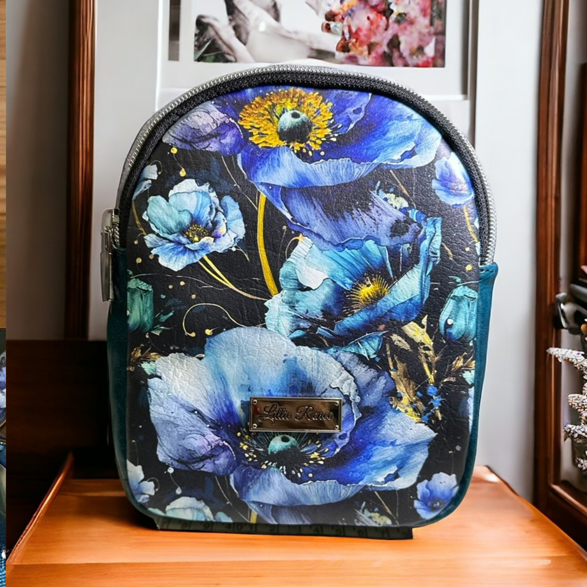 Small blue floral sling bag featuring a blue poppies vinyl exterior, a durable nylon webbing adjustable strap, and silver hardware. Designed for convenience and style, this compact sling includes an interior slip pocket for easy organization. Perfect for hands-free carrying while adding a floral touch to any outfit.
