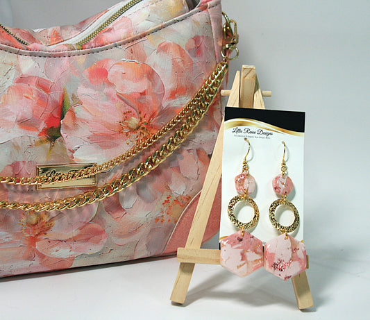 Floral handbag with gold chain and pink earrings on a stand
