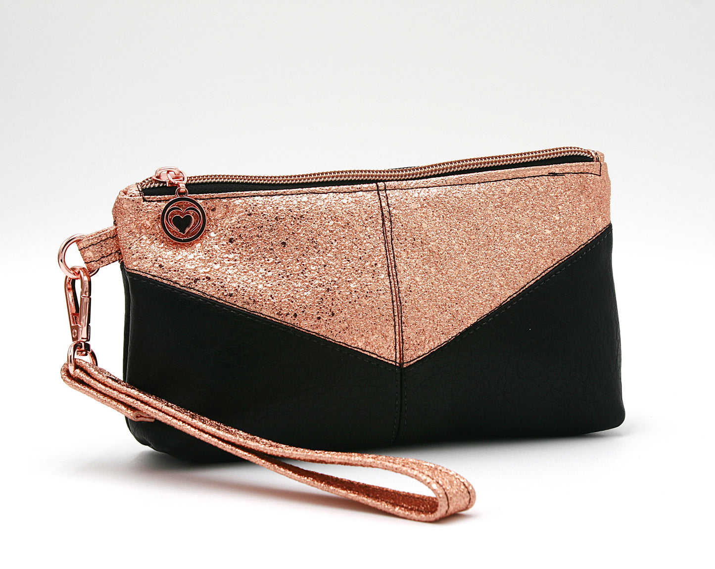 Small yet statement-making Harlequin wristlet, featuring copper vinyl and black faux leather, a soft cotton copper and black interior lining, and a convenient interior zip pocket. Finished with rose gold heart zipper pulls and hardware, this wristlet blends sophistication and practicality.