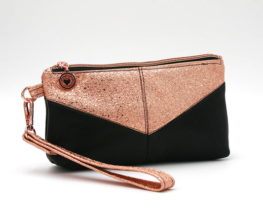 Small yet statement-making Harlequin wristlet, featuring copper vinyl and black faux leather, a soft cotton copper and black interior lining, and a convenient interior zip pocket. Finished with rose gold heart zipper pulls and hardware, this wristlet blends sophistication and practicality.