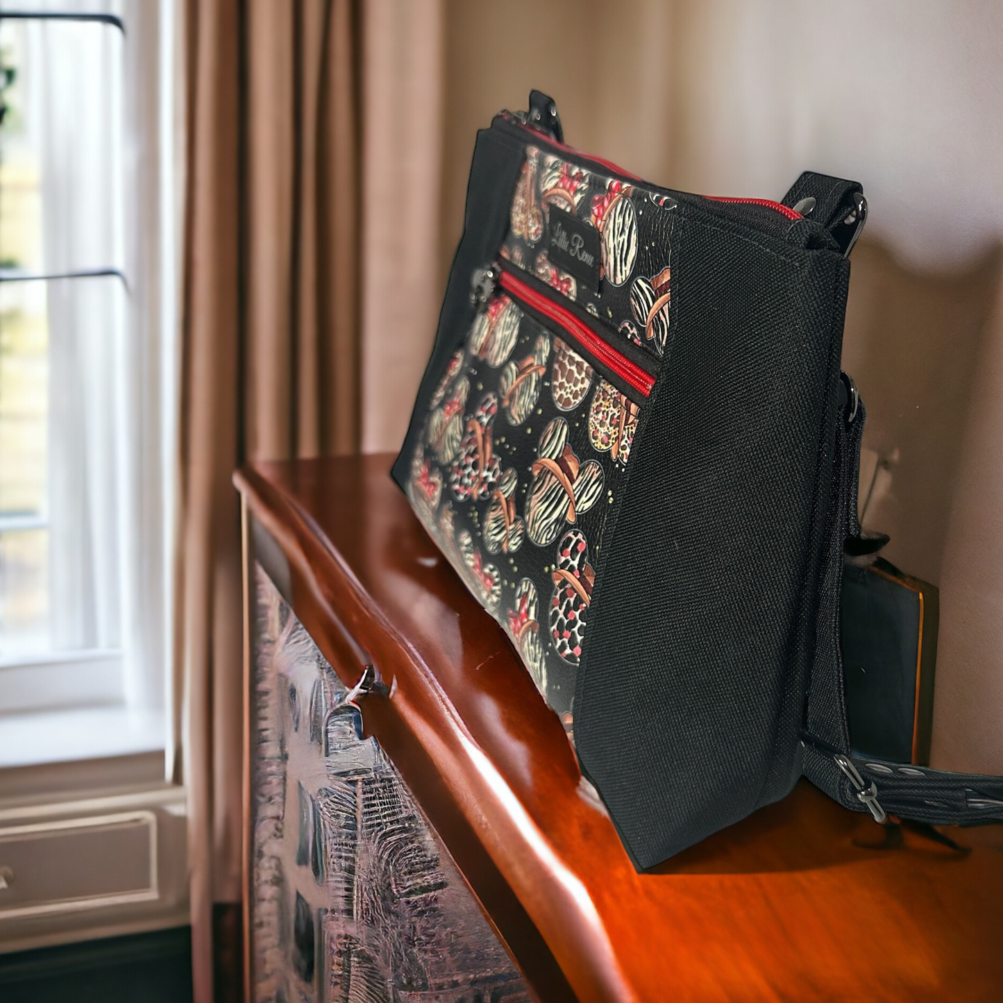  Mickey-themed crossbody purse with animal print vinyl and black canvas. Lined with a coordinating red and white cotton fabric, this medium crossbody handbag offers a spacious interior zipper pocket, an exterior zipper compartment, and an adjustable crossbody strap for comfort and versatility. A must-have for Disney fans, stylish travel bags, and unique fashion accessories.
